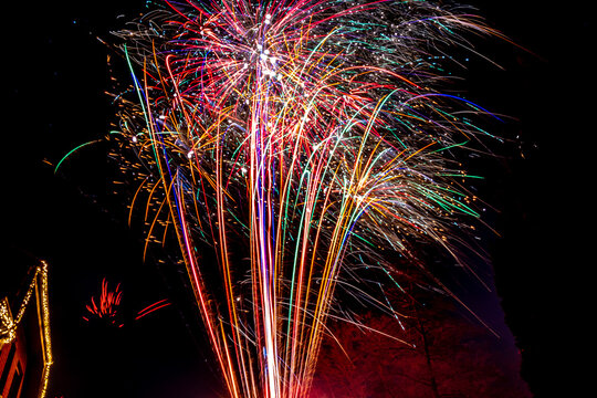 Farbenpr&auml;chtiges Silvester-Feuerwerk in originaler Umgebung mit Haus und Baum im Hintergrund