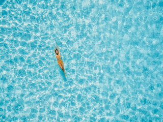Woman floating in transparent blue ocean. Aerial view, top view.