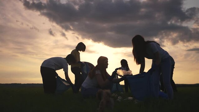 people collect garbage in bags at sunset. garbage collection help concept. a group of volunteers helps the environment fight waste. friendly team work together lifestyle and clean up nature together
