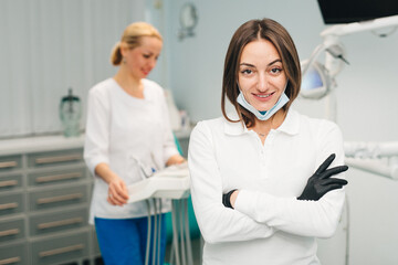 Fototapeta premium Woman doctor dentist on the background of a modern dental clinic. Work of a doctor and nurse in dentistry. The concept of advertising dental services and healthy teeth.