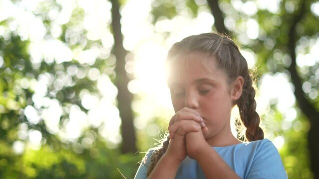 child pray. young gratitude a god religion concept. little girl in nature outdoors praying dreams of happiness to god. lifestyle praise worship freedom concept. kid praying in the forest