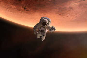 Astronaut is flying in outer space on Mars planet background. Elements of this image furnished by...