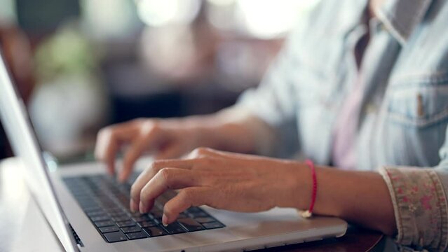 Asian senior woman types text working with laptop computer 