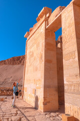 A woman looking at hieroglyphs  - Hatshepsut Temple at sunrise in Valley of the Kings and red cliffs western bank of Nile river - Luxor- Egypt