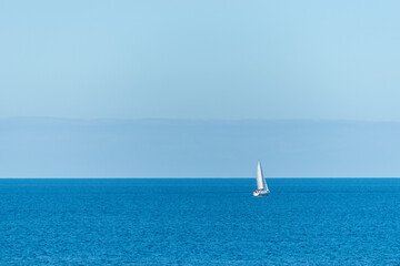 White sailboat at the beautiful blue sea.
