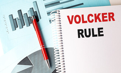 VOLCKER RULE text on a notebook with pen on a chart background