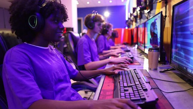 close-up on woman playing online video games with her group of gamer friends in uniform in the background