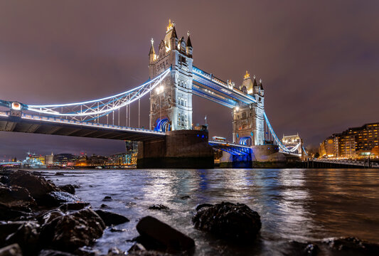 Iconic Tower Bridge in London spanning over river Thames at evening twilight with colorful illumination at christmas time. Landmark, sight and tourist attraction in english metropole from river bank.