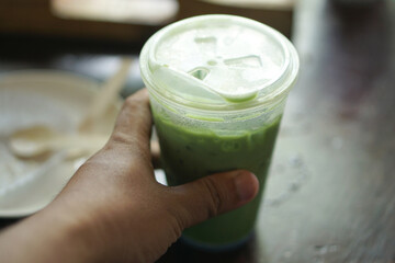 Human hand holding a glass of iced green tea