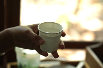 Human hand holding a paper drinking glass