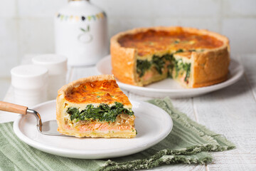 Sliced Spinach, cheese, onion and salmon fish tart or quiche. White background.