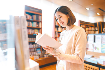 Portrait of young adult southeast asian woman reading book at bookstore shop