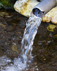 Fresh water emerging from a pipe. Image illustrating water scarcity and importance of fresh clean water in the environment.