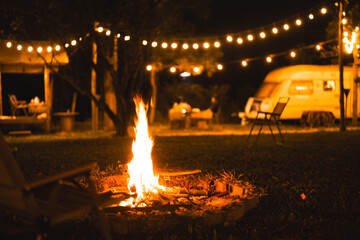 Exploring the wilderness in summer. A glowing camp fire at dusk providing comfort and light to...