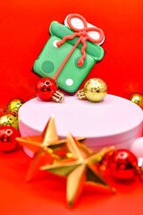 Imagen vertical de una galleta de navidad en una plataforma blanca con adornos de navidad sobre un fondo rojo aislado navideño 
