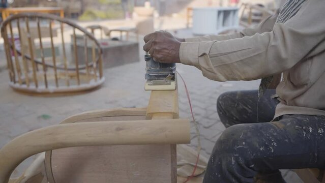 Carpenters use a sander to sand the surface of the wood to smooth the woodwork before painting, man of carpenter working with machine on chair stock video 

