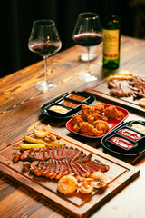 Variety of raw beef meat steaks for grilling with seasoning and utensils on dark rustic board, red tone of fresh food in raw cut