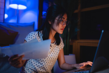 Late-night freelancer, Dedicated Asian woman working overtime on laptop computer, meeting deadlines...