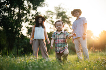 Obraz premium happy harmonious Asian family outdoors concept, Asian mother and son have activities happy fun together on holidays, grass land with sunlight