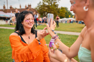 Obraz premium Two Female Friends Looking At Glitter Make Up At Summer Music Festival
