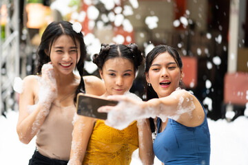 Selfie photo on mobile phone. Foam party summer entertainment, Group of three Happy smiling sexy young woman and friends on beach foam party