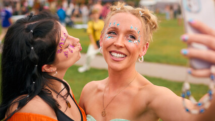Two Female Friends Wearing Glitter Posing For Selfie At Summer Music Festival