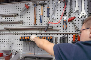 A worker selects a tool for work and repair in a locksmith workshop.
