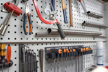 Square slot screwdrivers, keys and various tools hang on a rack in a locksmith workshop.