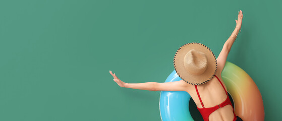 Relaxing young woman in swimsuit and with inflatable ring on green background with space for text - obrazy, fototapety, plakaty