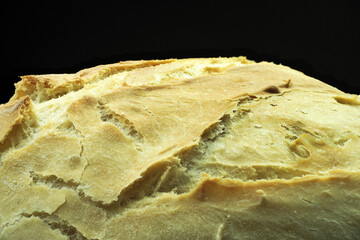 Freshly baked white bread from white flour, on a black background.