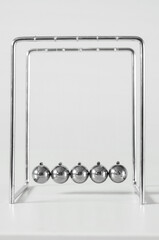 Newton's Cradle on table near light wall