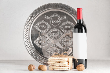 Bottle of wine, Passover Seder plate, flatbread matza and walnuts on light background