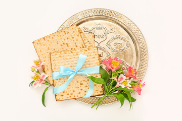 Passover Seder plate with flatbread matza and alstroemeria flowers on white background