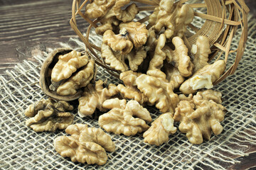 Peeled walnuts lie in a basket on a dark table.