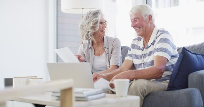 Senior couple, laptop and bills for budget, financial assets and planning pension investment at home. Happy man, woman and documents for online banking, tax savings or insurance policy for retirement