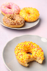 Plates with sweet donuts on light background