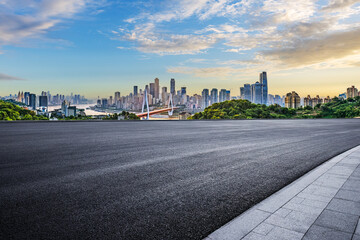 Empty asphalt road and city buildings skyline at sunset
