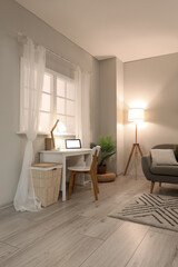 Interior of living room with grey sofa, workplace and glowing lamp