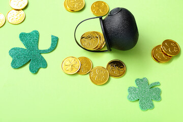 Pot with coins and paper clovers on light green background. St. Patrick's Day celebration