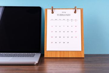 February 2024 desk calendar and laptop