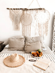 Romantic scandi boho style bedroom interior with wicker hat, fresh fruits and open book on bed