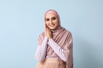 Young Muslim woman on blue background. Islamic New Year celebration