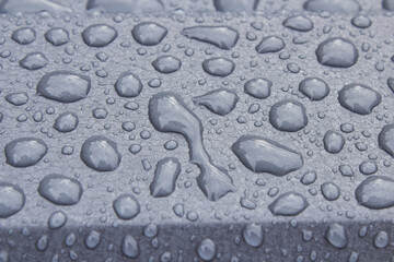 drops on metal in gray color, close-up of metal profile with cracked paint and raindrops