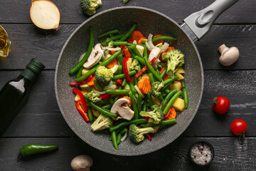 Frying pan with fresh vegetables on black wooden background - Powered by Adobe