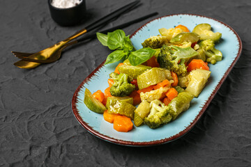 Plate with different fried vegetables on black background