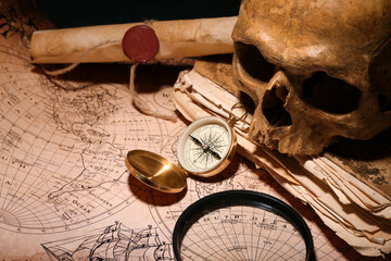 Human skull with old manuscripts, travel equipment and world map on black background