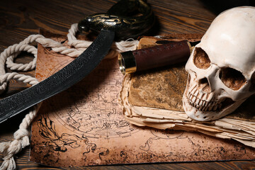 Human skull with old manuscripts, world map and travel equipment on brown wooden background