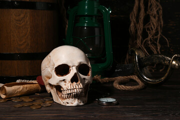 Human skull with sword, pocket watch, oil lamp and coins on brown wooden background