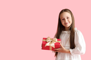 Little girl with gift on pink background