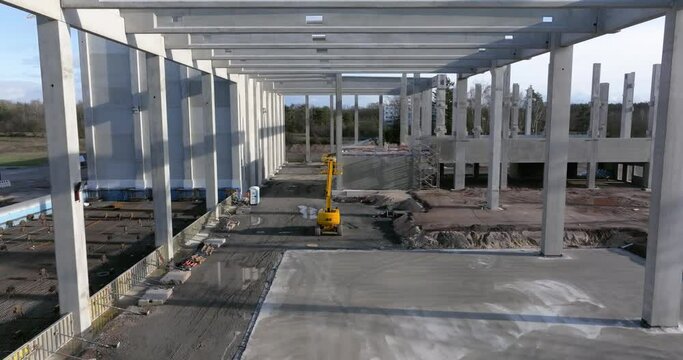 Drone video of a construction site of an industrial building with columns and beams and a heavy-duty crane